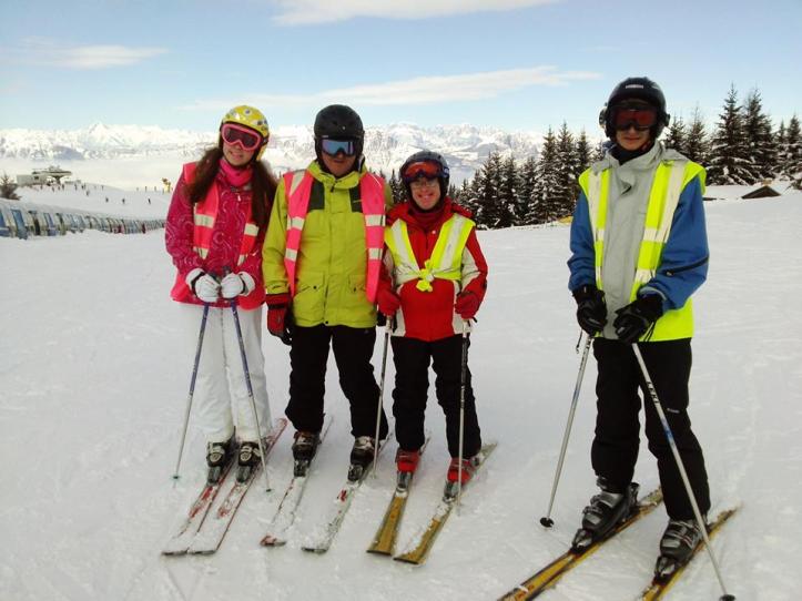 4 skiers stood at the top of a mountain smiling.