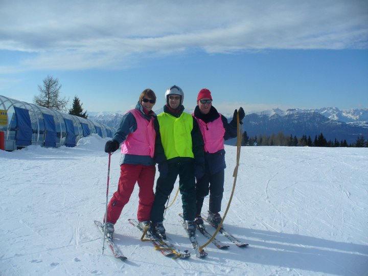 Disabled skier and 2 Guides stood at the top of a mountain.