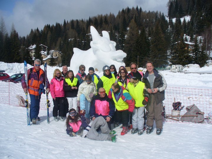 Group of people on the trip, stood in front of a snow sculpture in the shape of a cow.