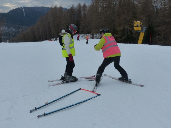 Guide demonstrating skiing technique to a disabled skier.